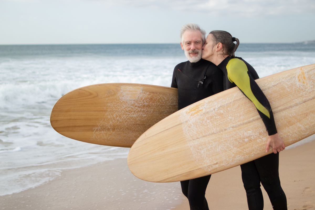 happy elderly couple going in for surfing together